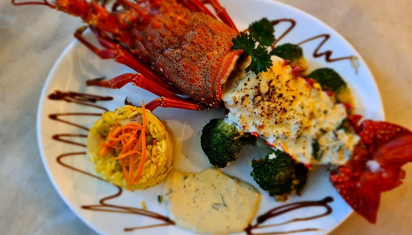 As the 'Diving Capital' and an active fishing port, fish is the absolute star. In the image, a grilled lobster dish.