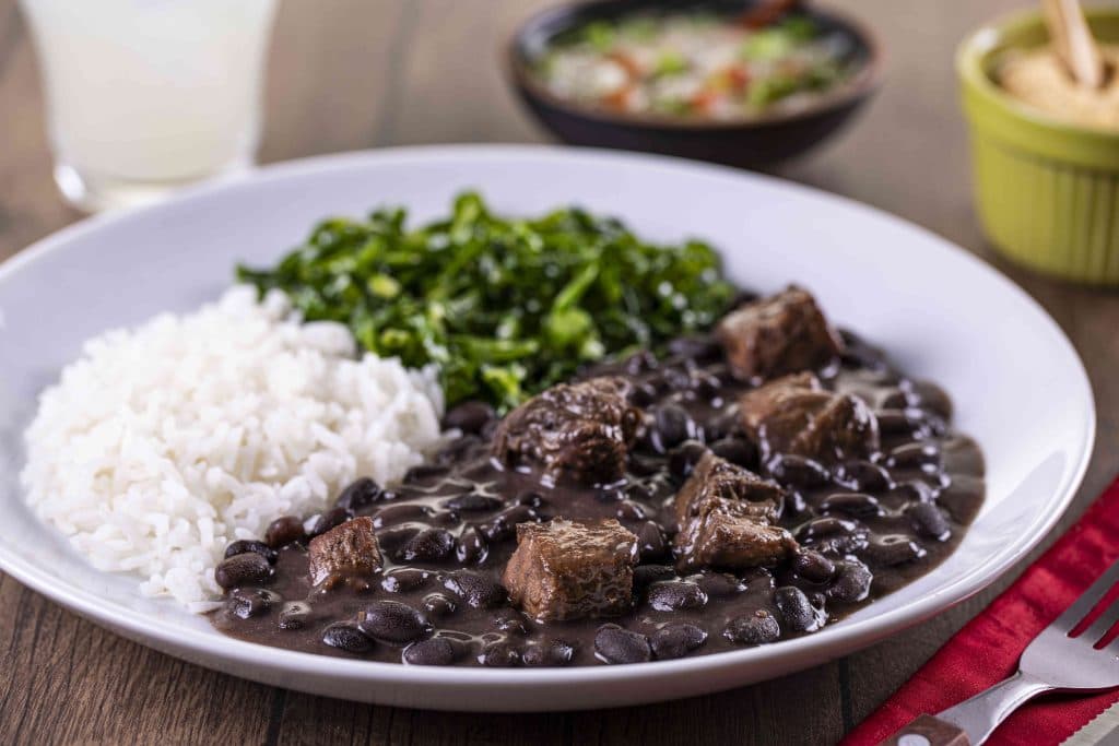 Feijoada. Considered Brazil's national dish, it is a hearty black bean stew cooked with different cuts of pork and beef. It is traditionally served with white rice, farofa (toasted cassava flour), orange slices and collard greens, and is commonly eaten on Wednesdays and Saturdays.