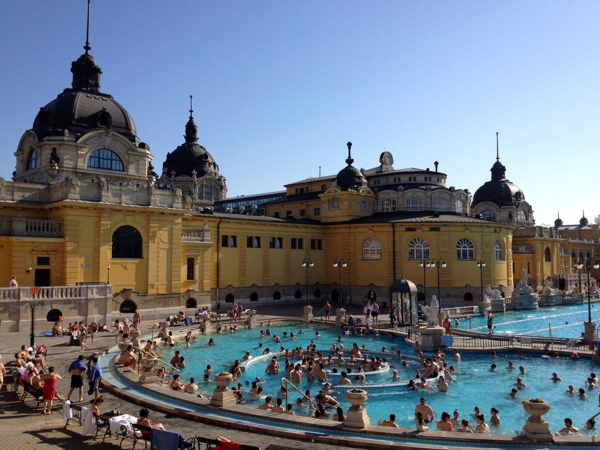 Las majestuosas piletas exteriores amarillas de los Baños Széchenyi en Budapest bajo el vapor termal.