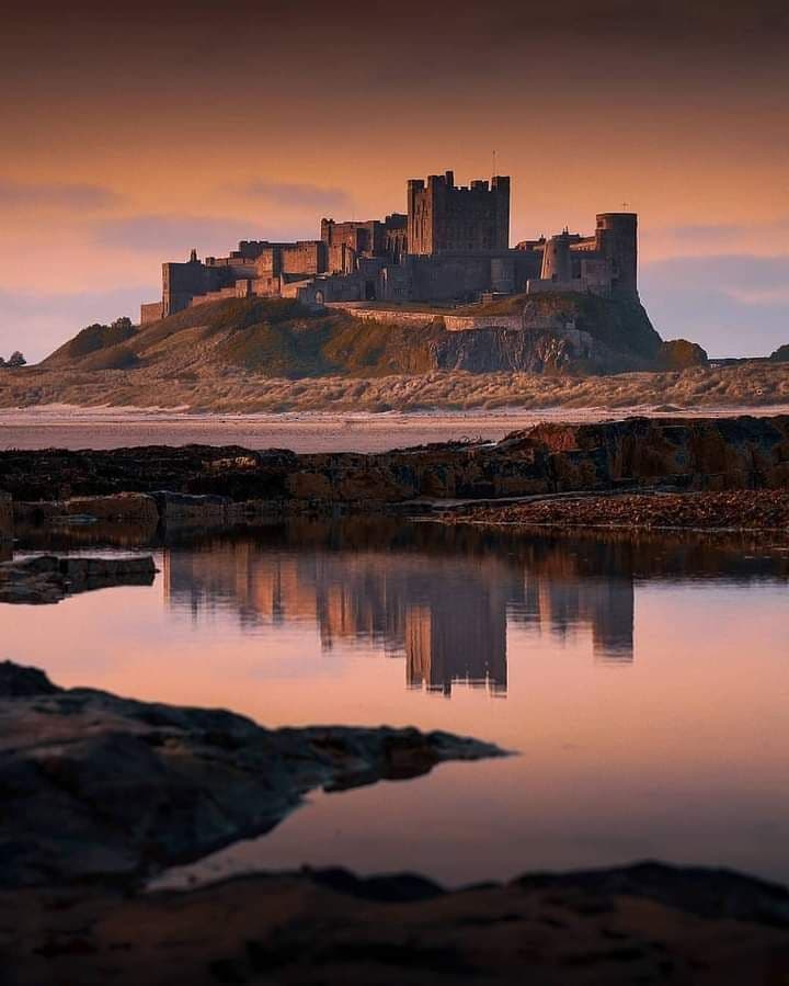 The majestic Bamburgh Castle seen from the sand dunes of Northumberland beach, England.