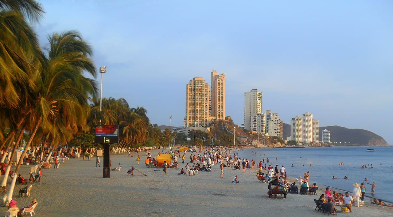 El Rodadero beach in Santa Marta, Colombia, with buildings facing the sea and palm trees.