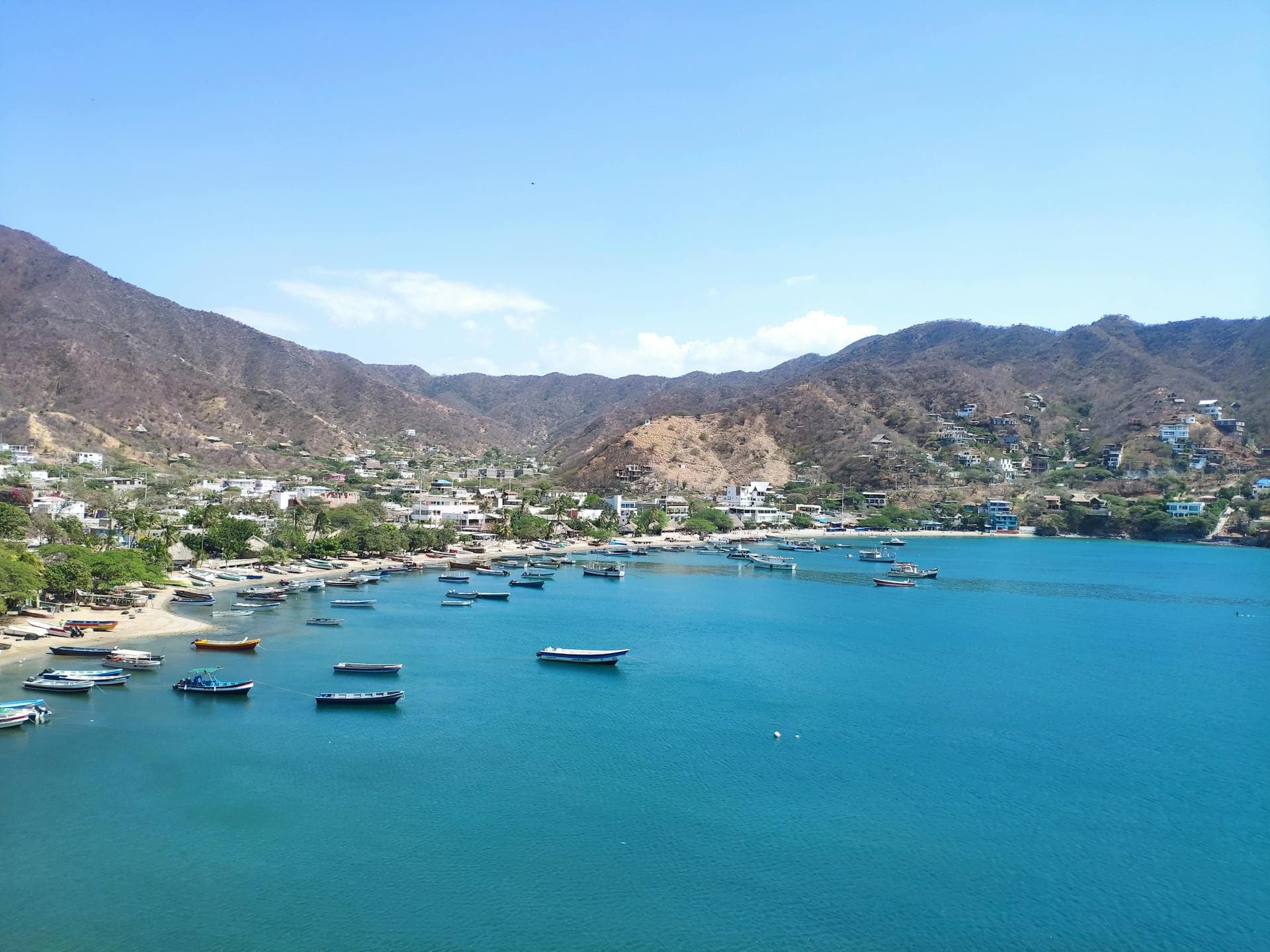 Playa Grande in Taganga, Santa Marta, Colombia, featuring a green-water bay and a hillside trail.