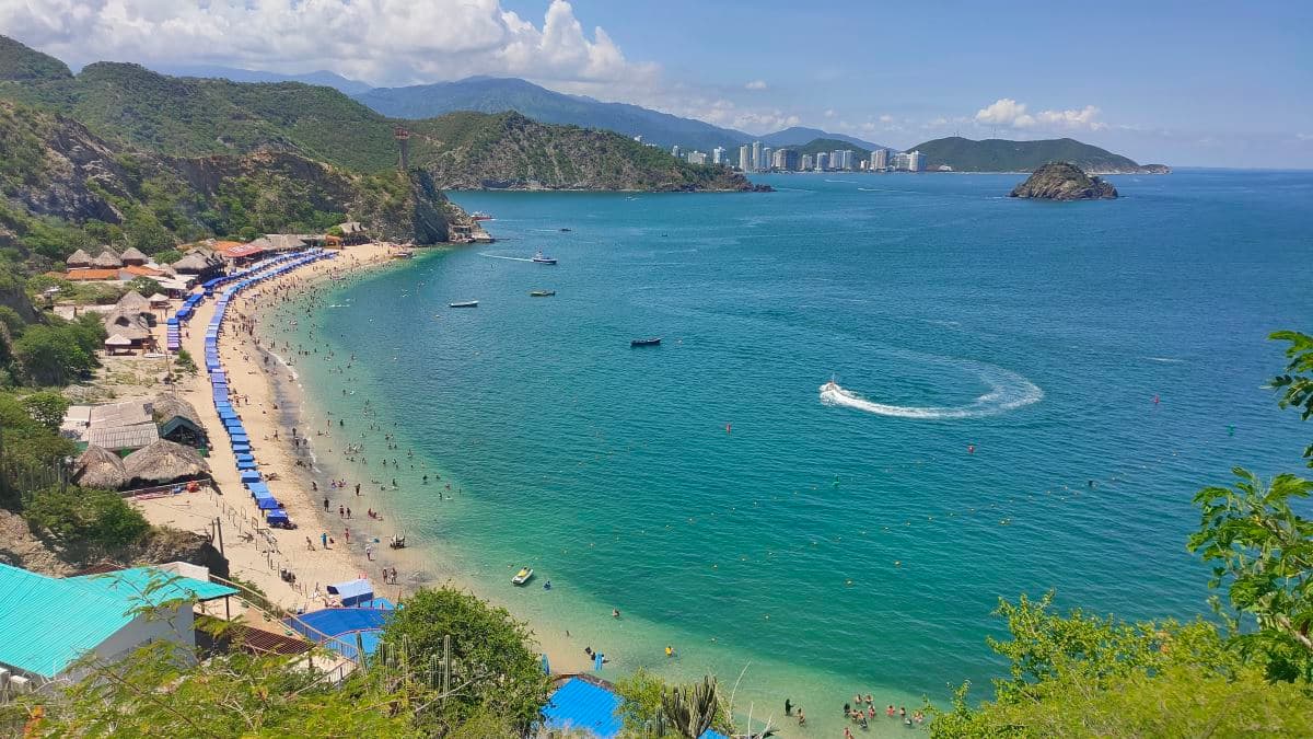 Playa Blanca in Santa Marta, Colombia, seen from the sea with arid hills and crystal-clear waters.