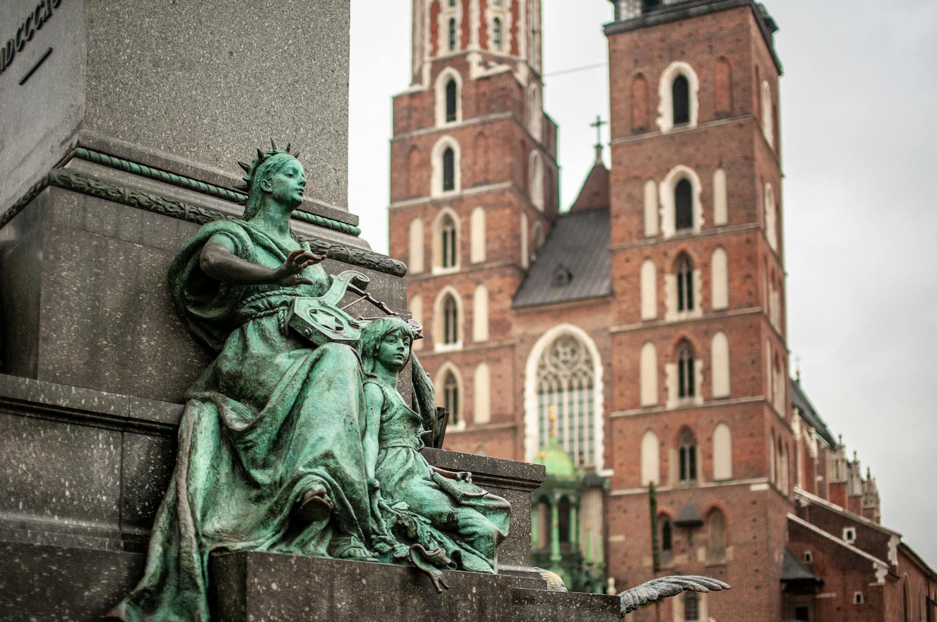 Estatua con la Iglesia Mariacki de Cracovia al fondo, resaltando la arquitectura europea.