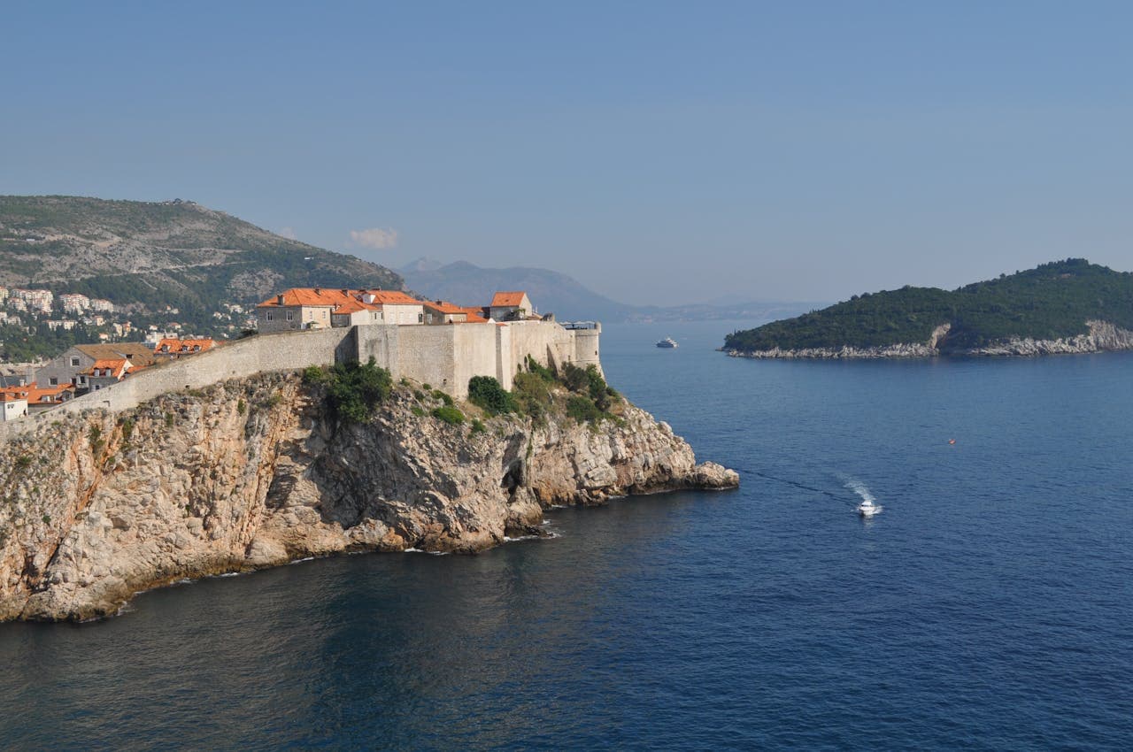 Dubrovnik walls on the cliff overlooking the Adriatic Sea with Lokrum Island in the background.