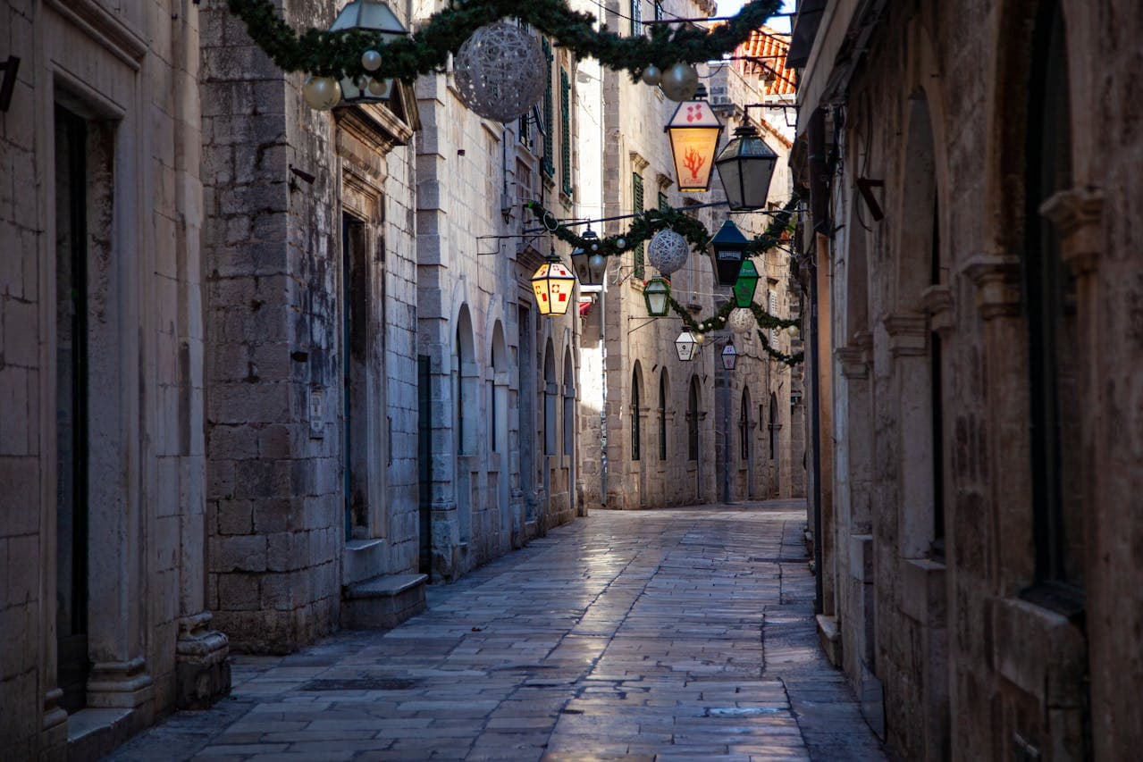 Medieval alley in Dubrovnik, Croatia, with traditional lanterns and limestone façades.
