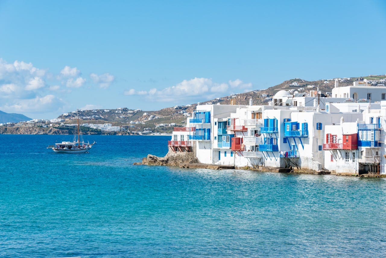 White facades of two- and three-story buildings facing the coast of Mykonos, typical Cycladic architecture.