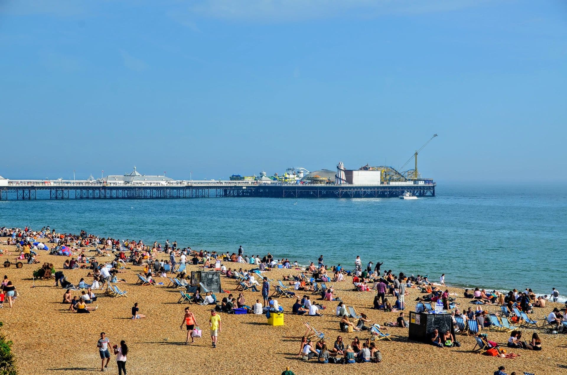 Gente en la playa de Brighton de fondo el clásico muelle de la ciudad, Inglaterra.