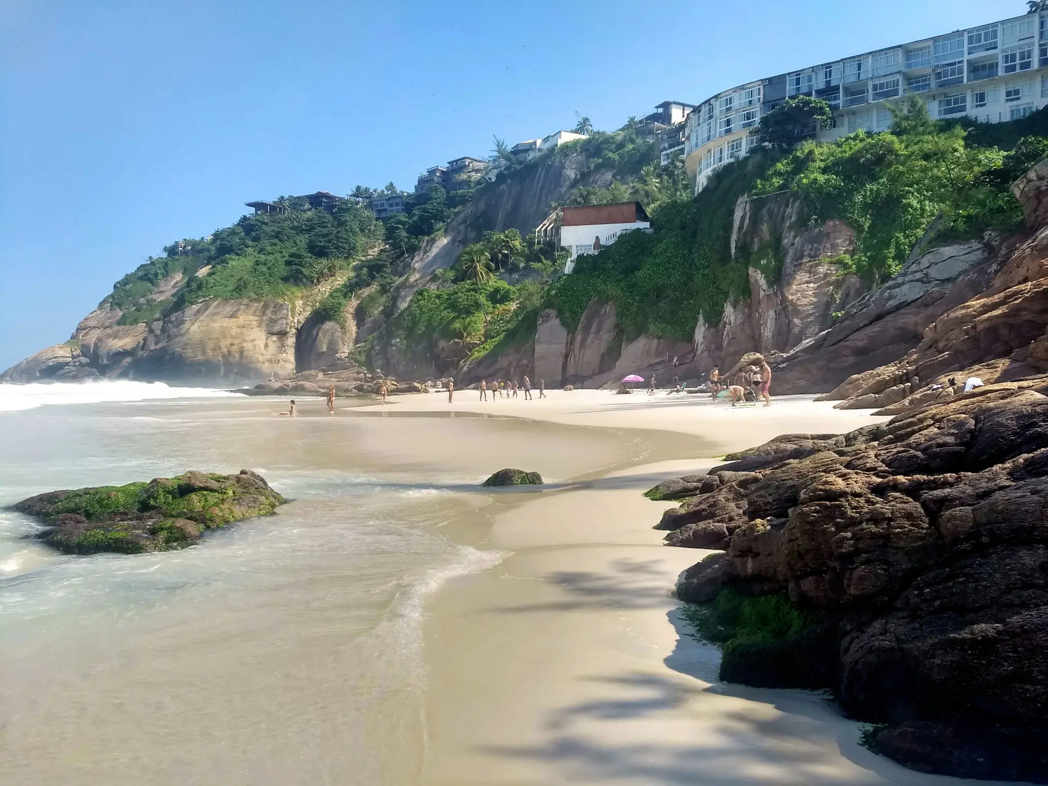 Panoramic view of Praia da Joatinga set between rocks and turquoise sea in Rio de Janeiro.
