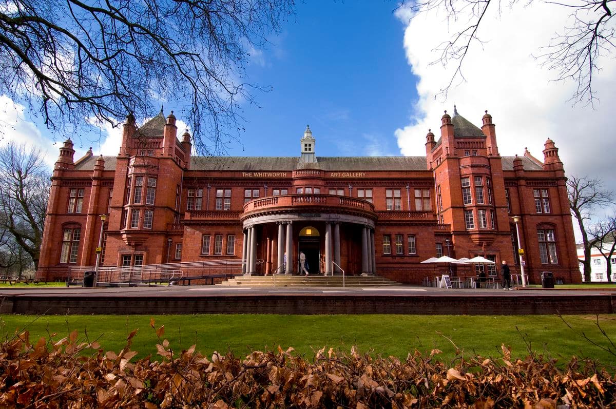 Modern glass structure of The Whitworth art gallery harmoniously integrated with the park in Manchester, England.
