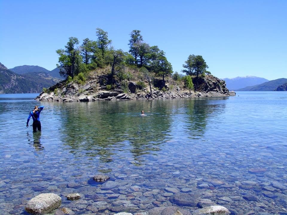 Gente disfrutando del sol y el lago un día de verano en playa La Islita, San Martín de los Andes.