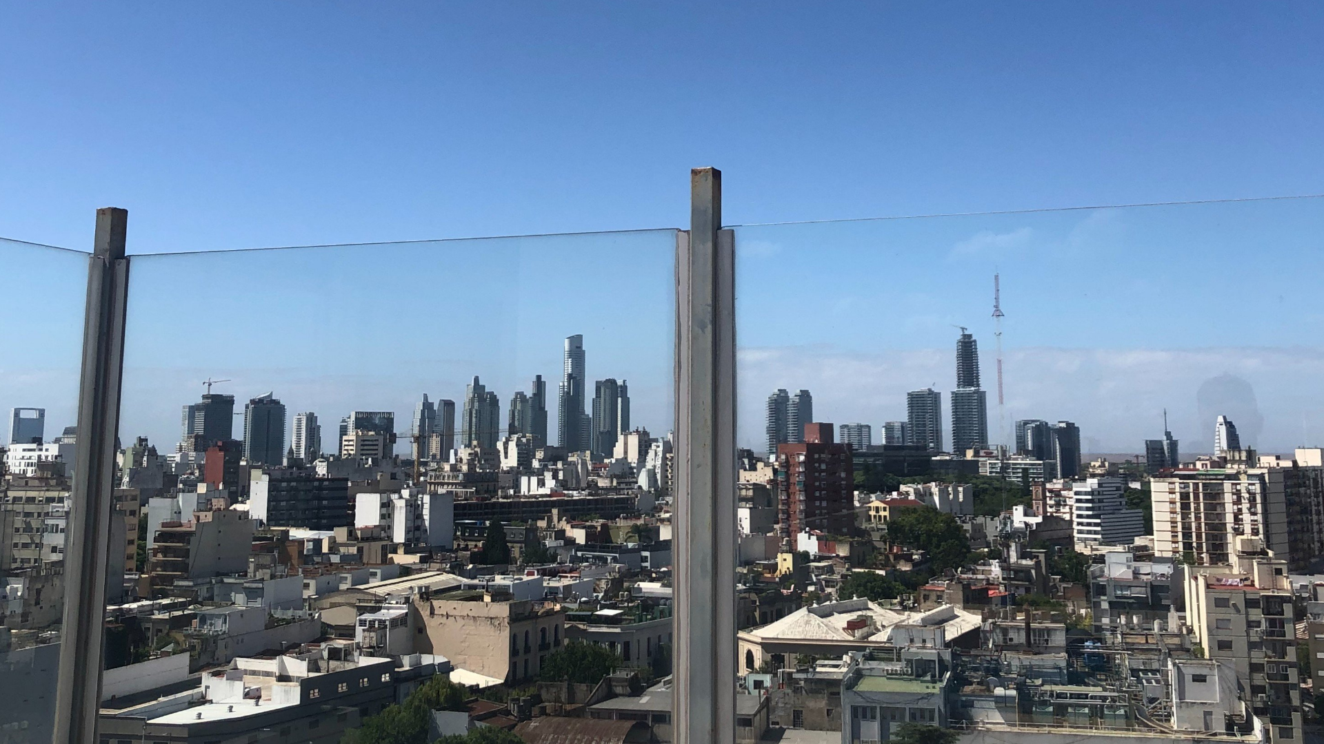 Vista panorámica de la ciudad en dirección al Río de La Plata. De fondo puede verse el barrio de Puerto Madero, es el barrio más joven, moderno y exclusivo de Buenos Aires. Ubicado frente al Río de la Plata, representa la transformación de un antiguo puerto abandonado en un centro de rascacielos de lujo, oficinas corporativas y gastronomía de alto nivel.