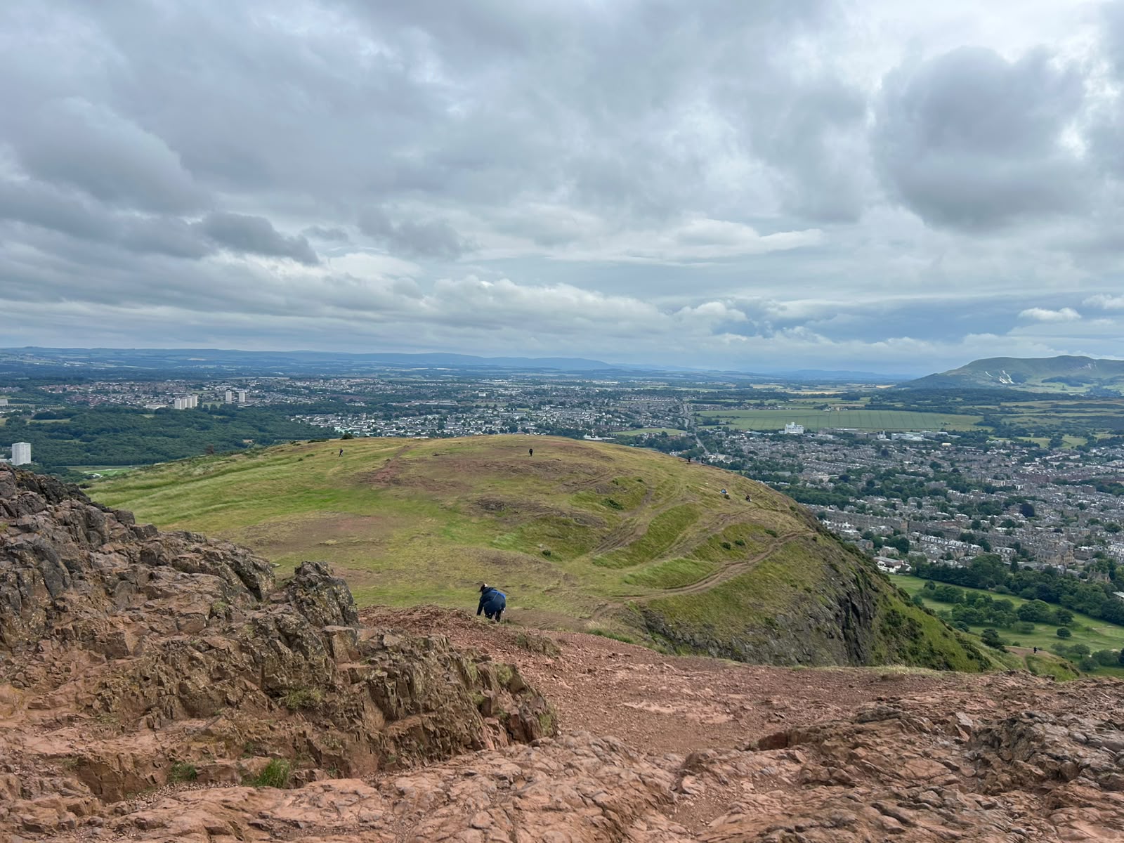 Detalhe das formações rochosas e trilhas íngremes que sobem em direção ao cume do vulcão Arthur's Seat de Edimburgo, Escócia.