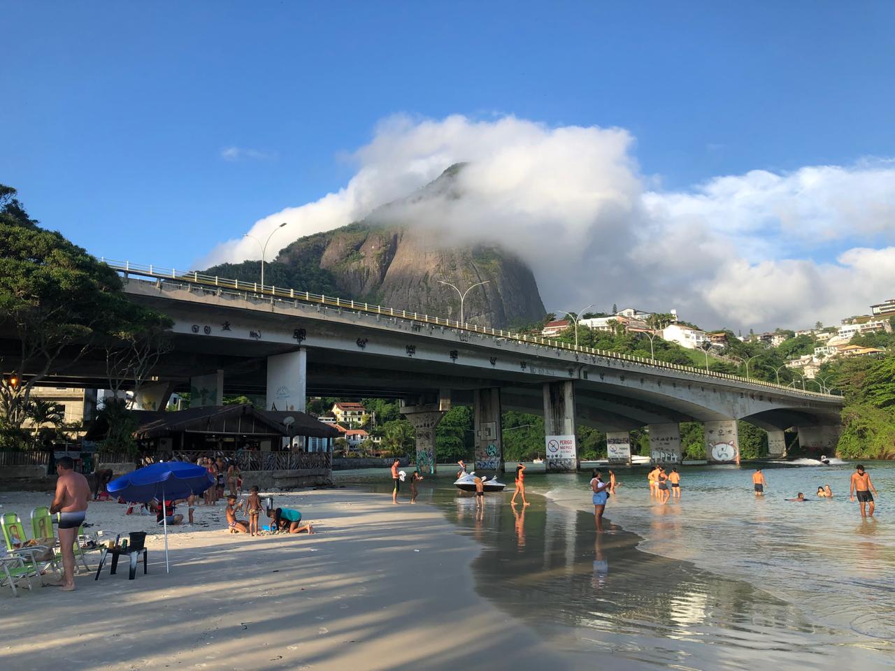 Gente local disfrutando y nadando en las calmas aguas del canal y riachuelo que desemboca en el mar al inicio de Barra da Tijuca.