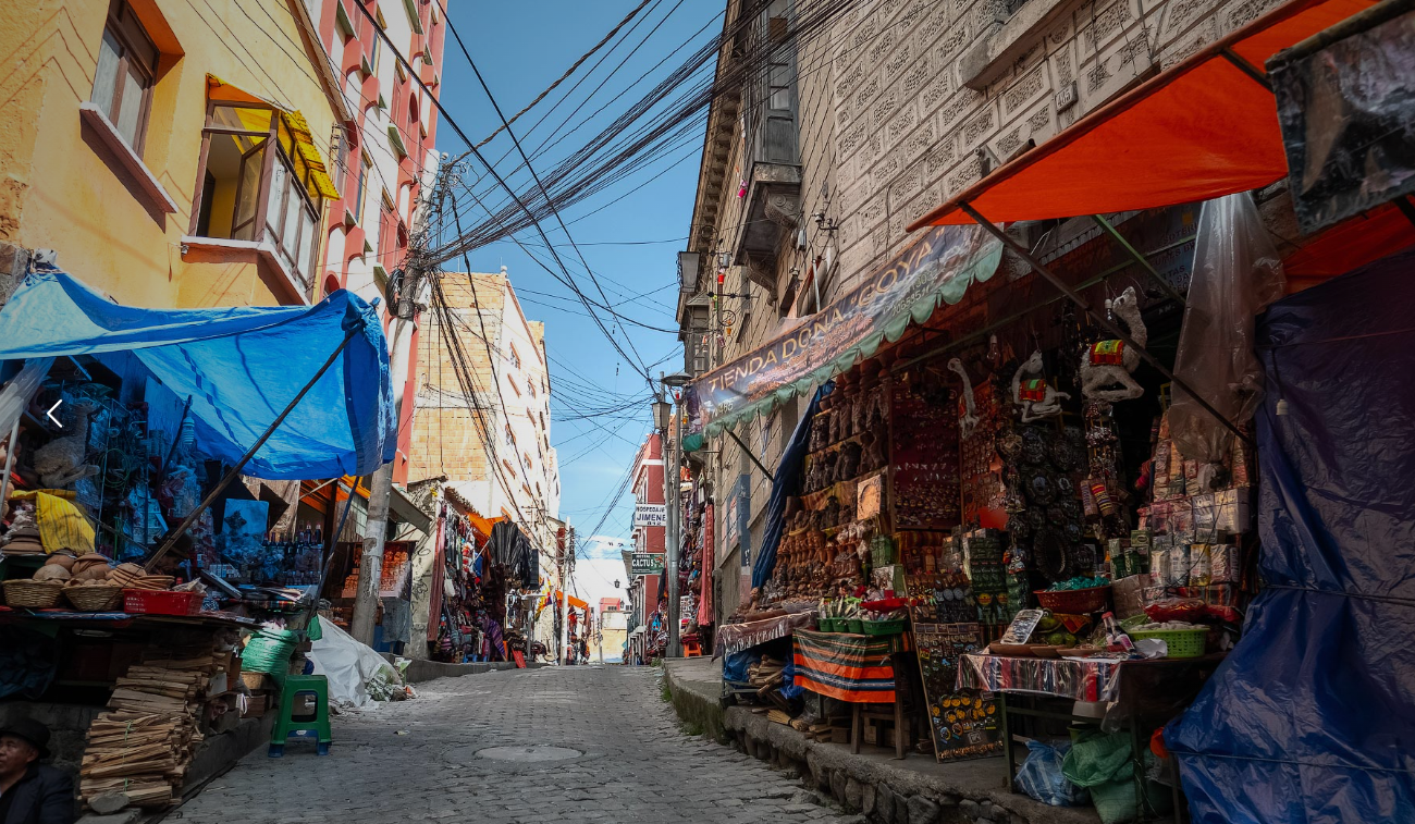 Mercado tradicional boliviano con productos locales y vestimenta típica.