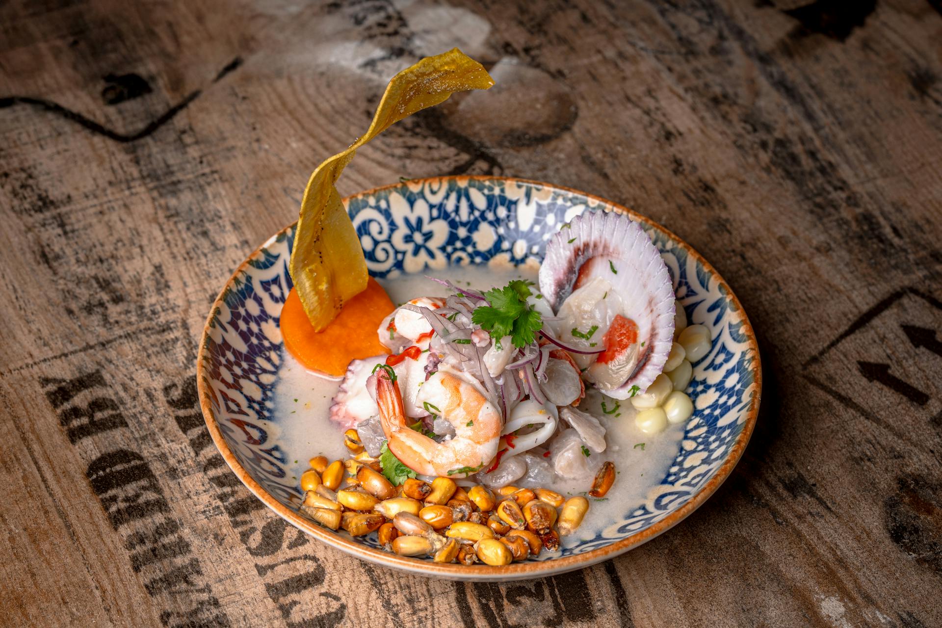 Un vibrante plato de ceviche con camarones, leche de tigre y maíz en un plato estampado.