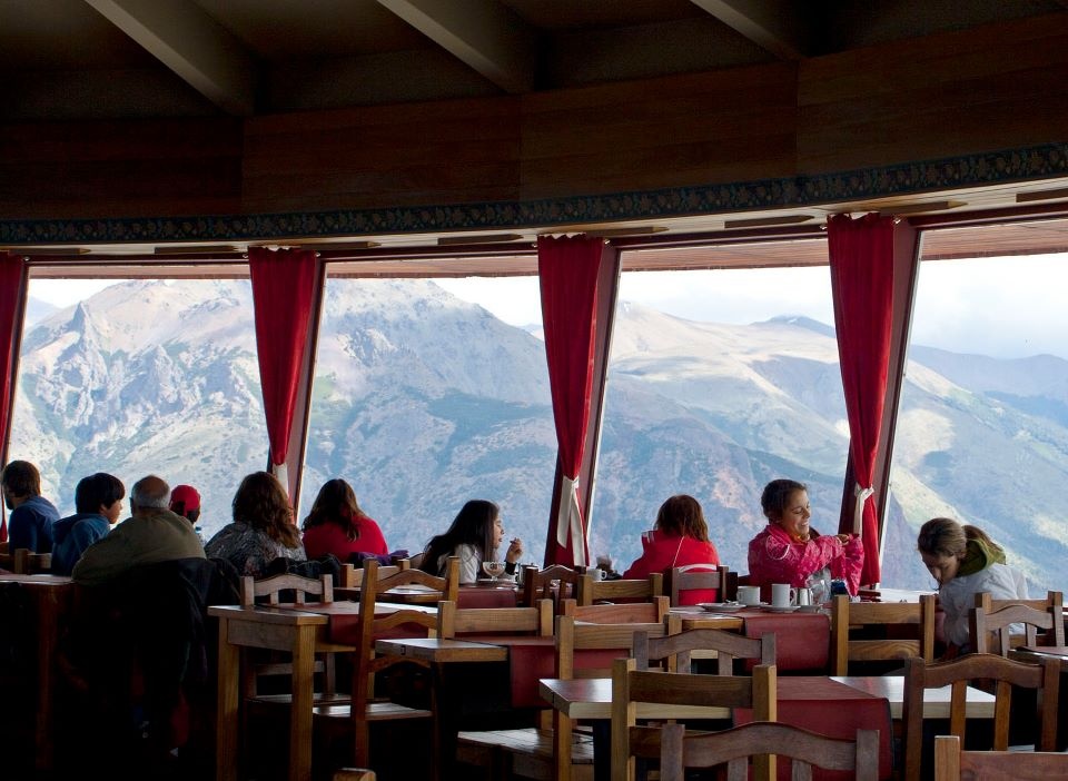 Interior of the Cerro Otto Revolving Cafeteria showing tables next to the panoramic window with views of the Bariloche surroundings.