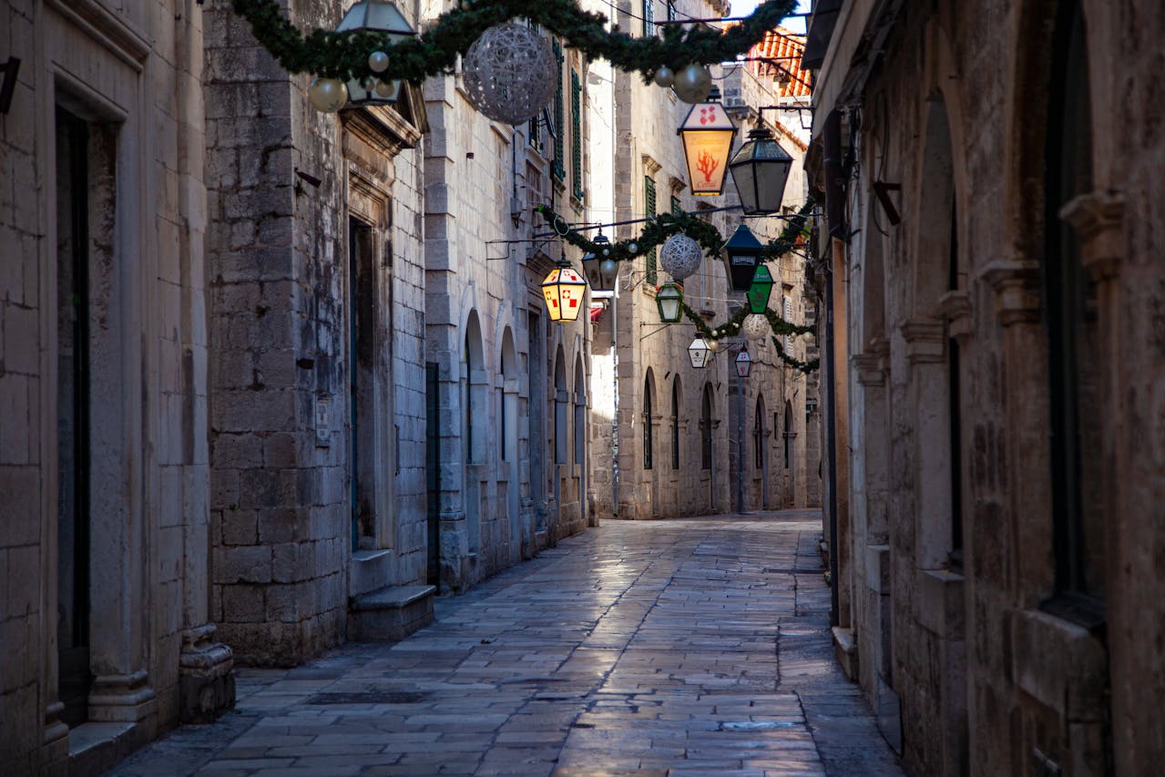 Callejón medieval en Dubrovnik Croacia con faroles tradicionales y fachadas de piedra caliza.
