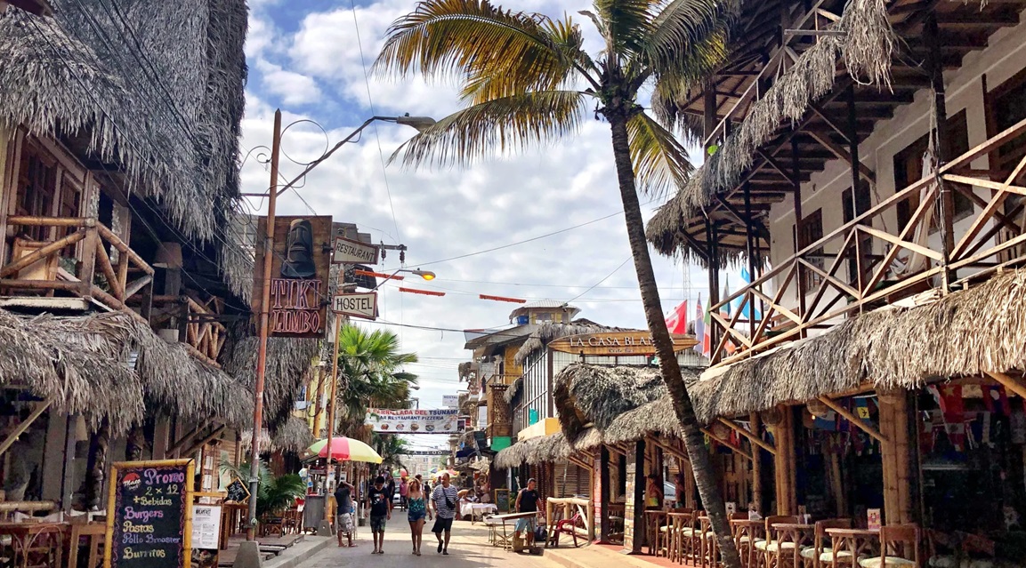 Calles coloridas del centro de Montañita, Ecuador, llenas de locales comerciales y ambiente bohemio.