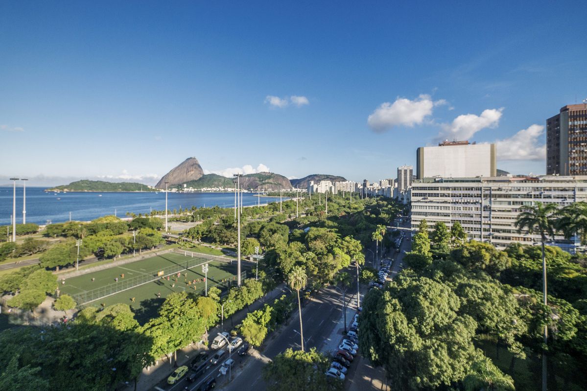 Vista panorâmica do Parque Aterro do Flamengo com suas palmeiras e caminhos, margeando a baía com vista para o Pão de Açúcar no Rio de Janeiro, Brasil.