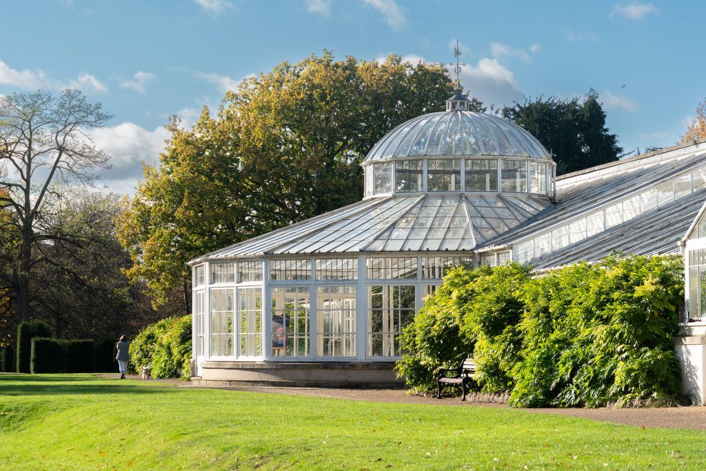 O espetacular pavilhão Kibble Palace iluminado pelo sol entre os jardins do Jardim Botânico de Glasgow.