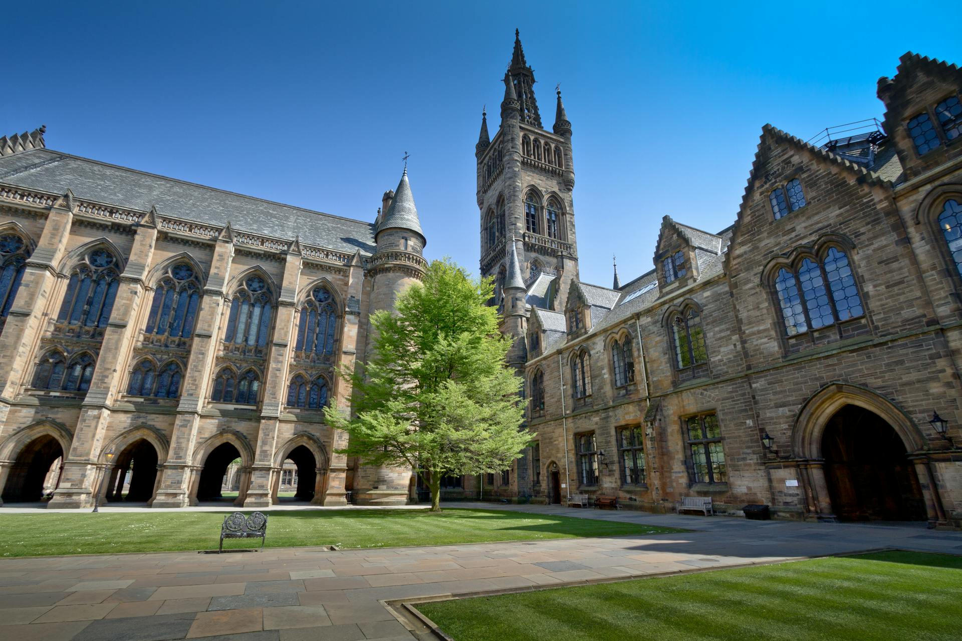 Vista del impresionante patio histórico de la Universidad de Glasgow bajo un cielo azul claro.