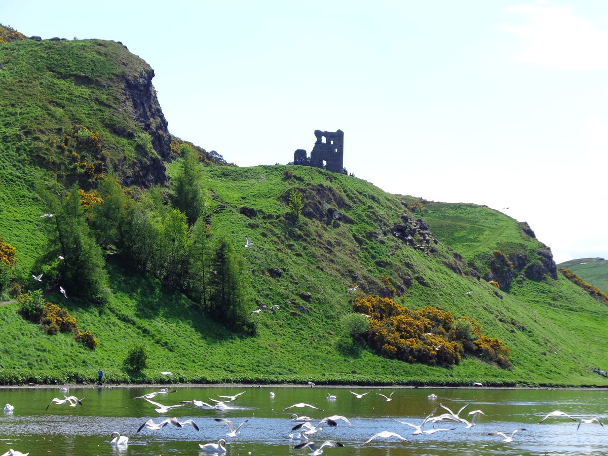 The stone ruins of St Anthony's Chapel on a grassy hill in Holyrood Park, Edinburgh.