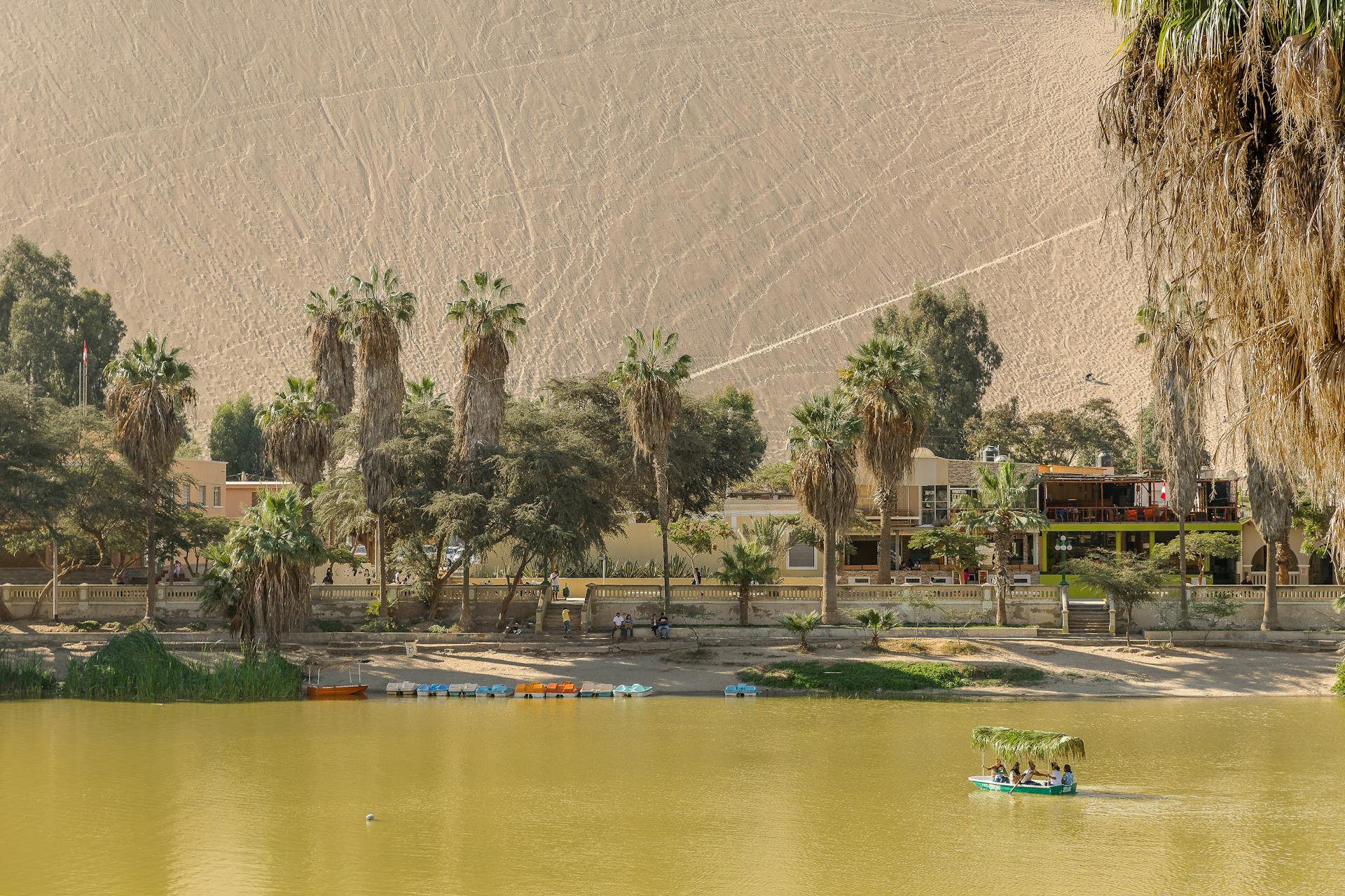 Vista del Oasis de Huacachina rodeado por las inmensas dunas del desierto de Ica, Perú.