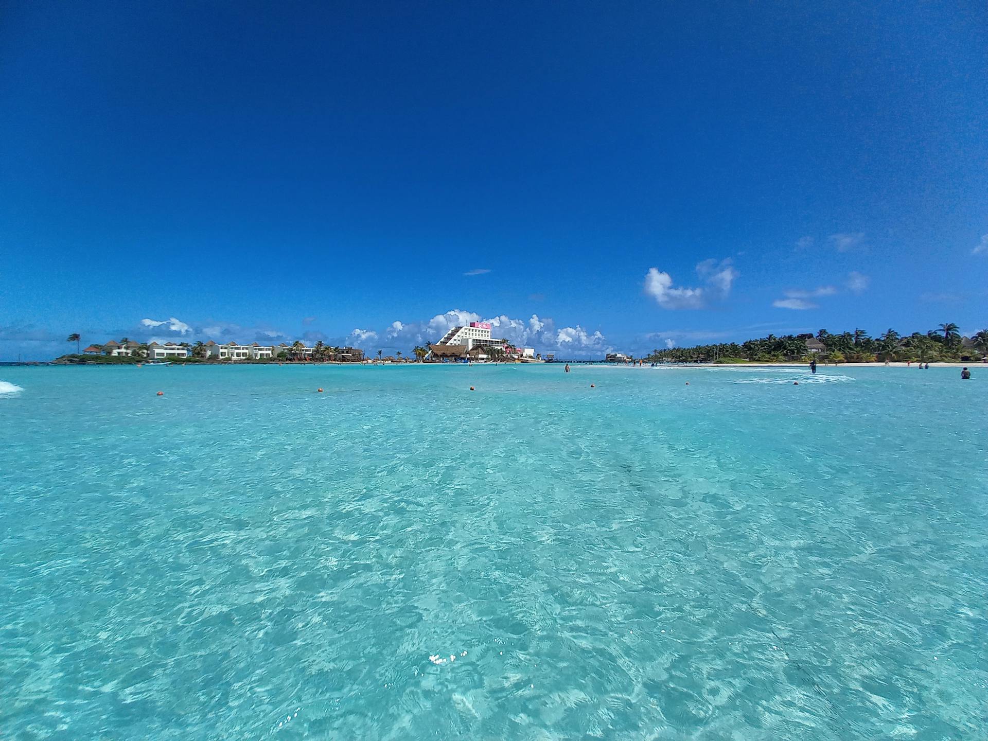 Vista desde el mar de Playa Norte en Isla Mujeres con agua turquesa y palmeras.