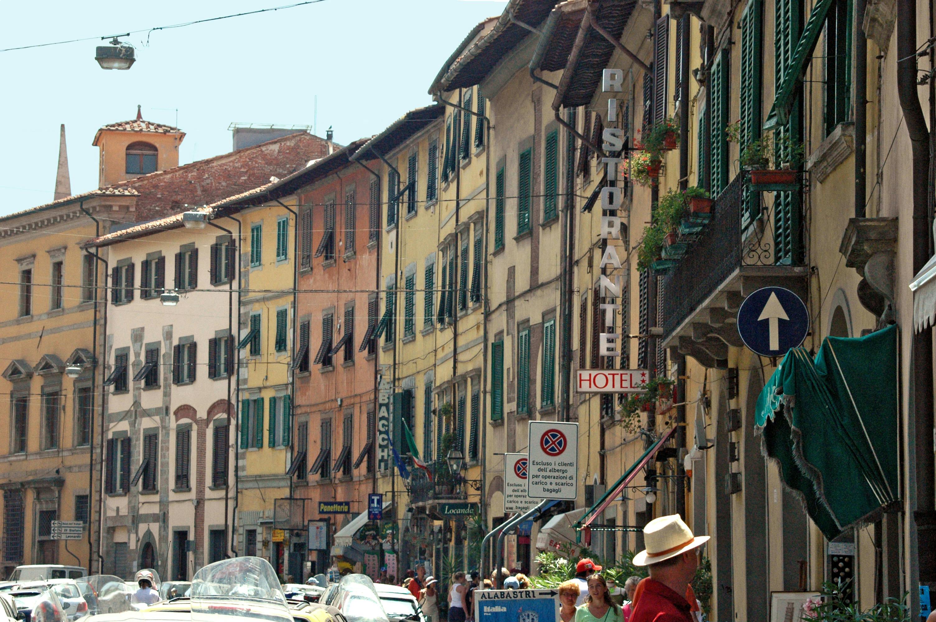 Vista de una calle típica italiana con fachadas de colores y flores en los balcones.