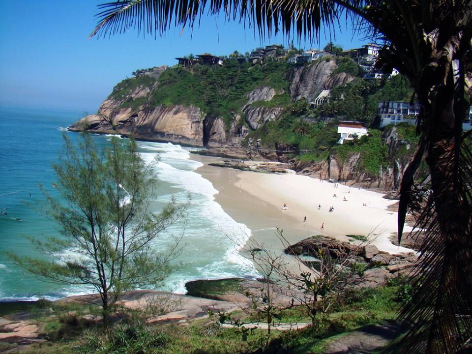 Vista panorâmica das falésias para as águas turquesas e a faixa de areia da Praia da Joatinga no Rio de Janeiro.