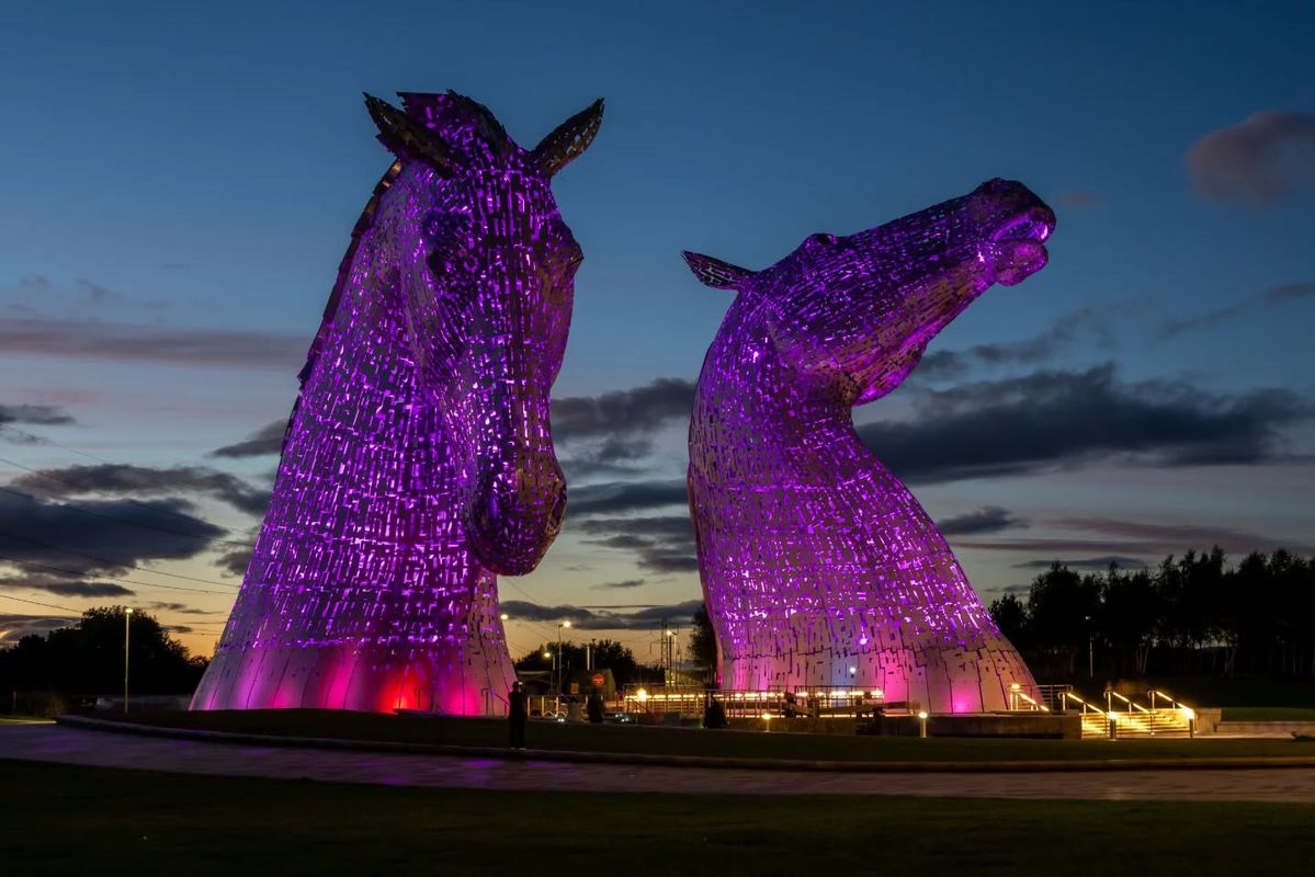 As duas monumentais cabeças de cavalo de Os Kelpies iluminadas à noite em Falkirk, Escócia.