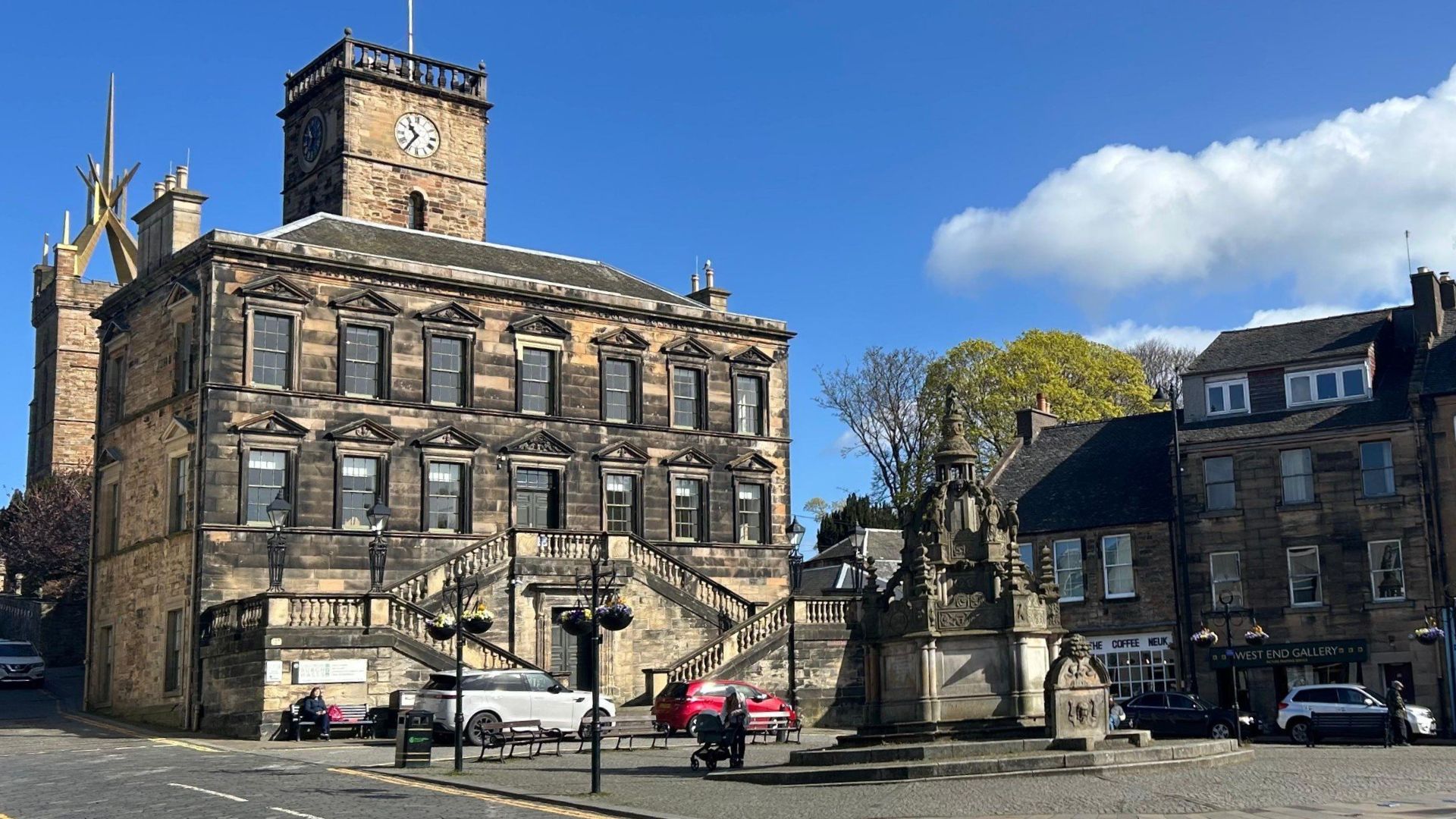 The heart of the Royal Burgh: the historic Cross Well fountain marks the main crossroads of the town, flanked by the old town hall and with the silhouette of the royal palace appearing behind.