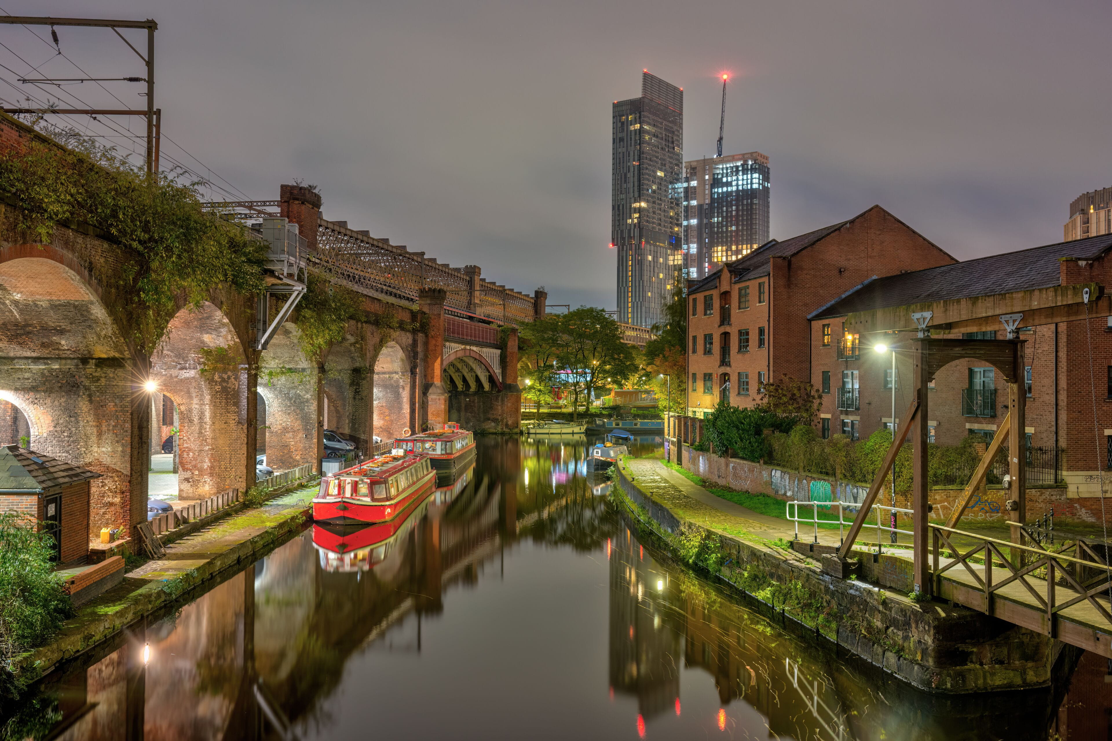 Vista de los canales de Castlefield en Manchester, con sus puentes de hierro y edificios de ladrillo visto tradicionales.