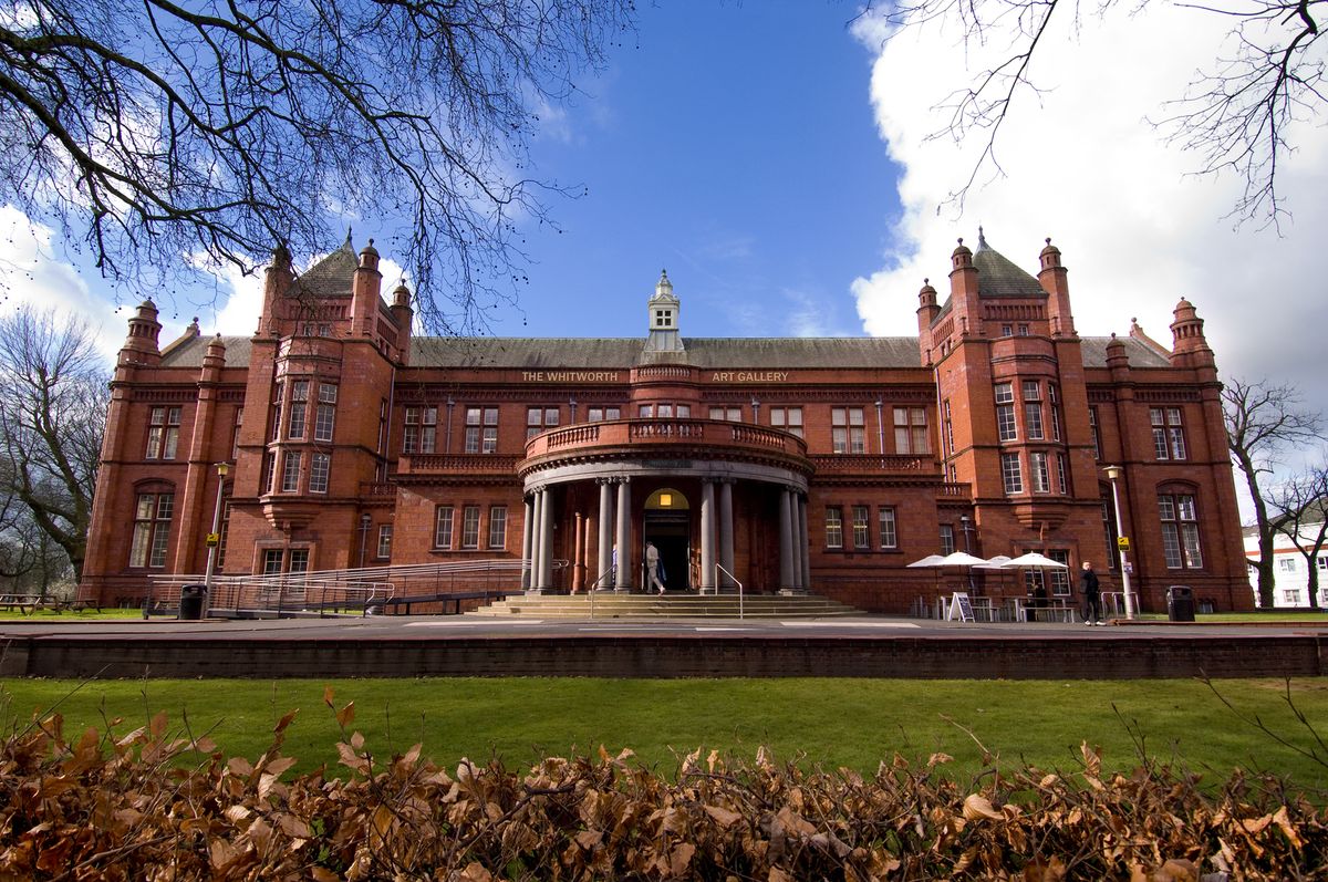 Estructura moderna de la galería de arte The Whitworth integrada armoniosamente con el parque de Manchester, Inglaterra.