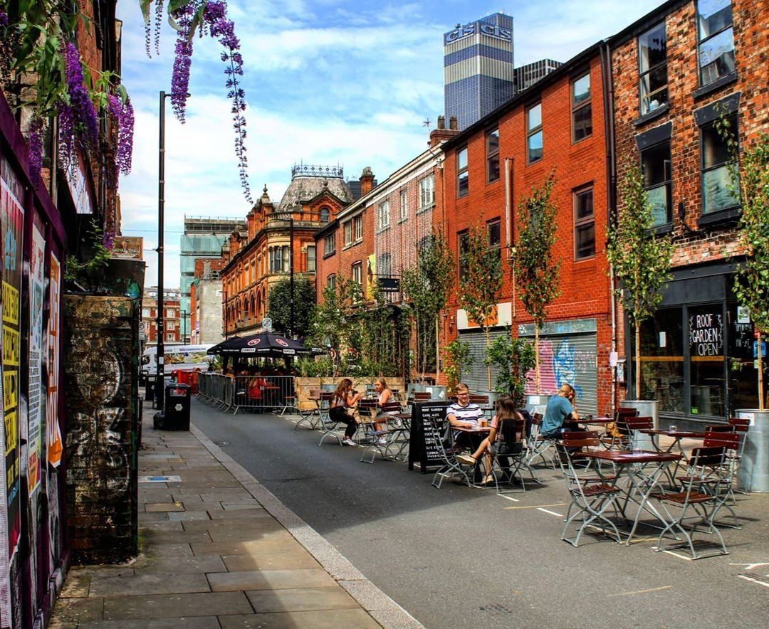 Locales gastronómicos entre edificios industriales de ladrillo recuperados alrededor de las plazas peatonales en el barrio moderno de Ancoats, Manchester, Inglaterra.