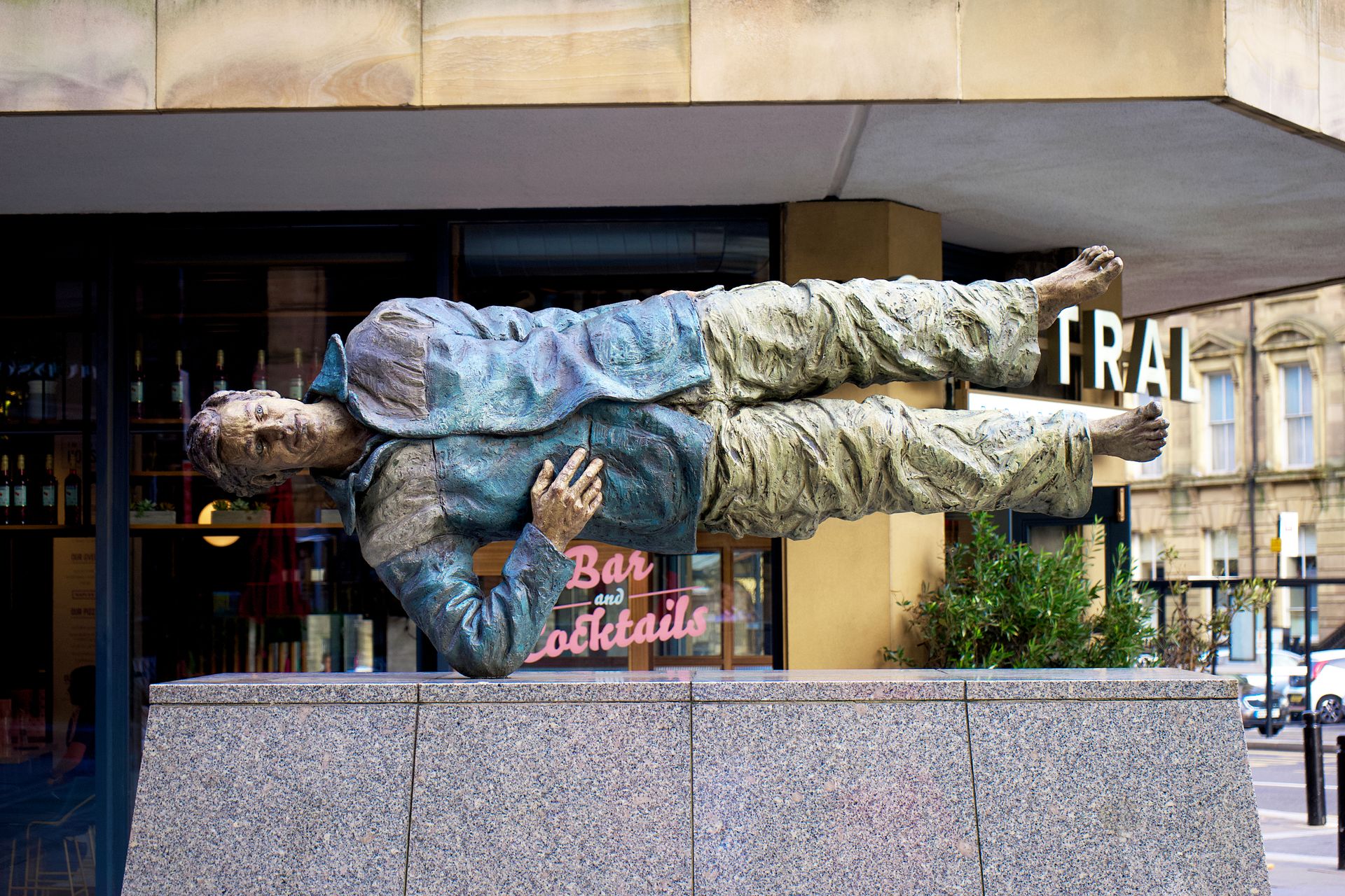 Urban bronze sculpture of a man performing a breakdance freeze on his elbow in central Newcastle upon Tyne.