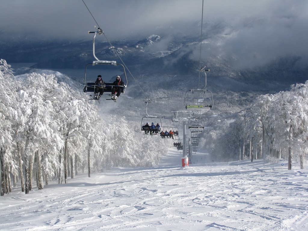 Chairlifts going up the snowy ski runs at Cerro Chapelco with the Lanín Volcano in the background.