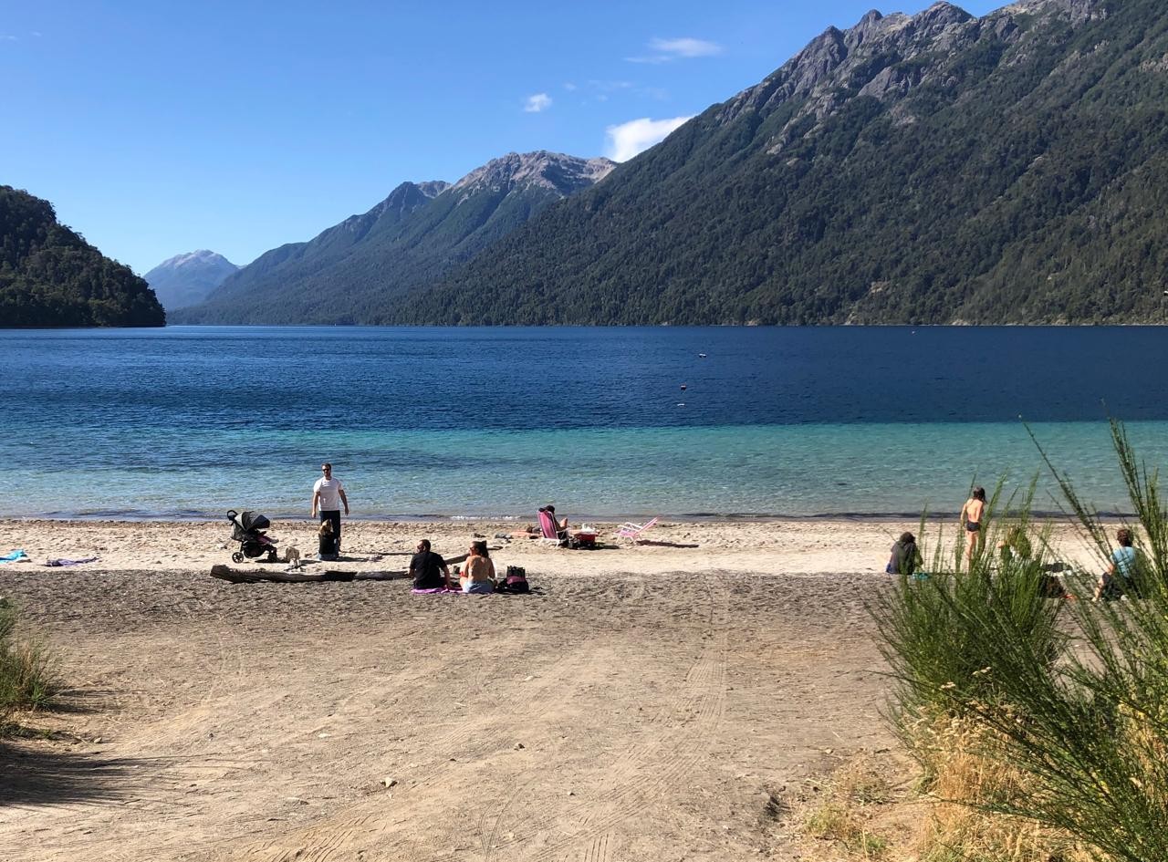 People enjoying the summer sun on the shores of Lake Correntoso, where the waters are slightly warmer.